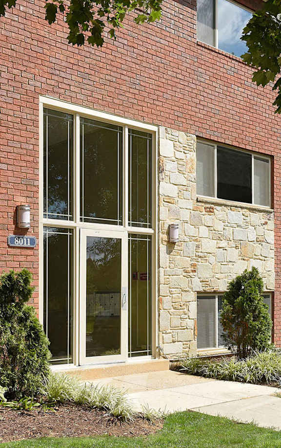 A red brick building with a glass door and windows at Cardiff Hall Apartments, Towson