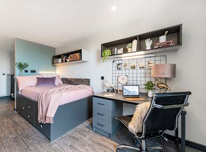 A bedroom with a bed, desk, and chair.