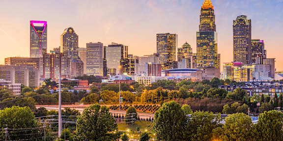 A city skyline at sunset with a prominent building in the center.