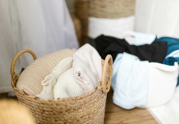a basket full of diapers on the floor next to a pile of clothes