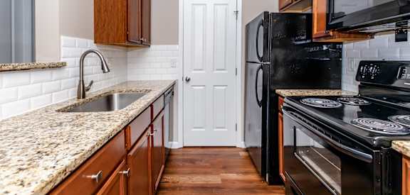 A kitchen with a black refrigerator and stove top oven.