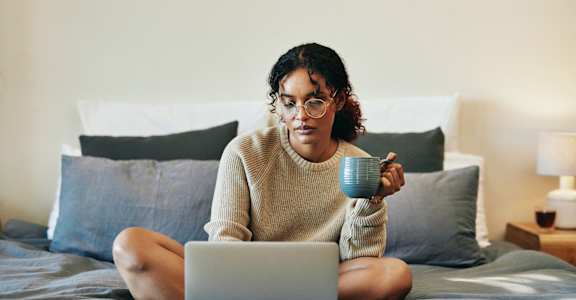 A Women is Sitting on a Bed with a Laptop at Estia Roseville Apartments, California