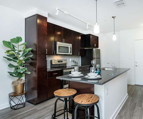 A kitchen with dark brown cabinets and a white countertop.