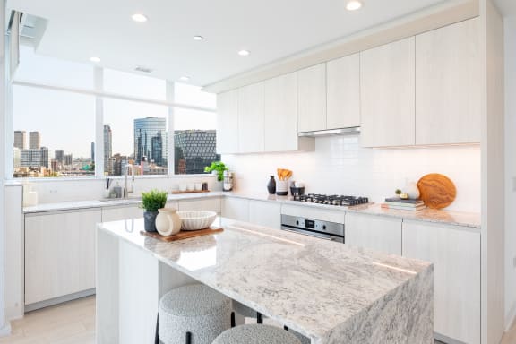 a kitchen with white cabinets and a large island with two stools