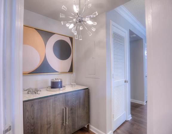a hallway with a cabinet and a chandelier and a door to a bedroom