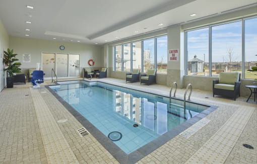 An indoor swimming pool with seating and large windows.