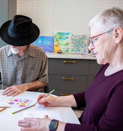 a man and a woman sitting at a table painting