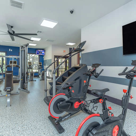 A gym with exercise equipment and a television on the wall.