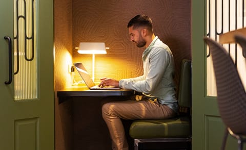 a man sitting at a desk using a laptop computer