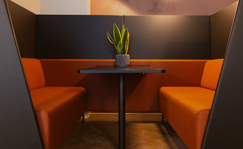 two orange chairs and a table with a potted plant