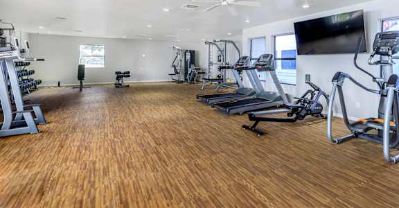 a gym with cardio equipment and a tv on the wall