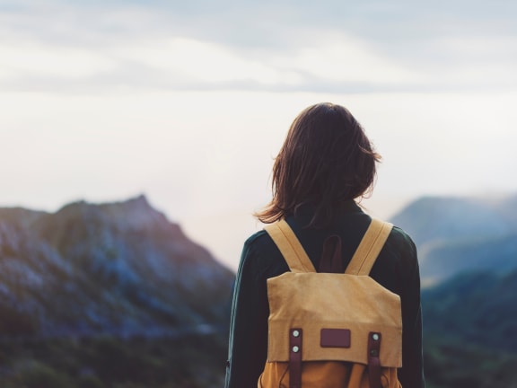 a woman with a backpack standing on top of a mountain