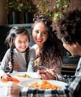 A family of three is having a meal together at a table.