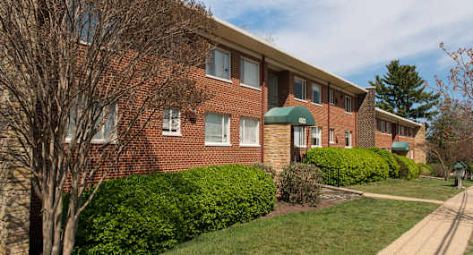 A brick building with a green awning sits on a street.