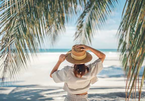 a woman wearing a straw hat looking out at the beach at Promenade at Carillon, St. Petersburg, Florida