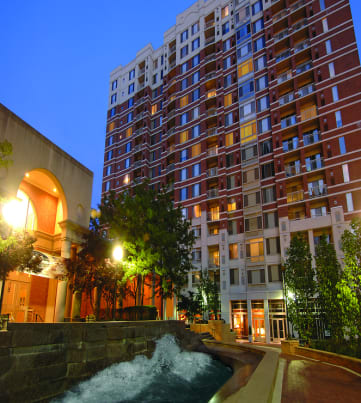 a city at night with a fountain in the foreground and a tall building in the background at The Bennington Apartments, Silver Spring, MD, 20910