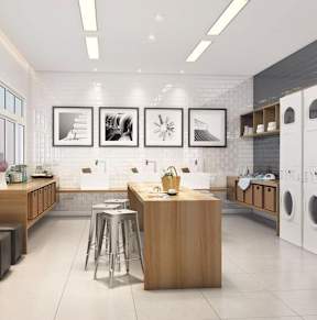 A modern laundry room with a washer and dryer, a counter, and a bar stool.