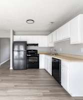 A kitchen with black appliances and white cabinets.at Lauradale, Jacksonville, 28540