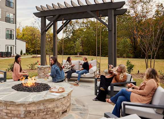 A group of people are sitting around a fire pit in a courtyard.