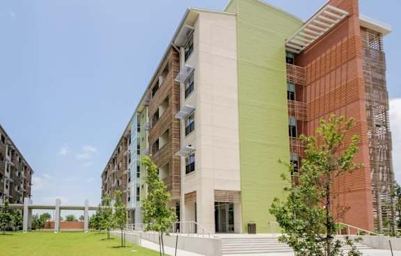 A modern building with a green and red facade stands under a clear blue sky.