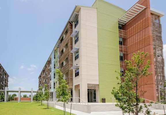 A modern building with a green and red facade stands under a clear blue sky.