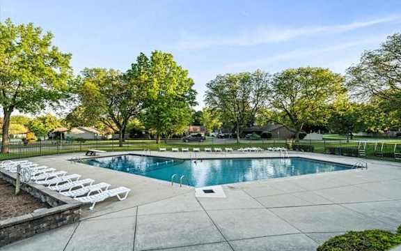 a swimming pool with white chairs around it