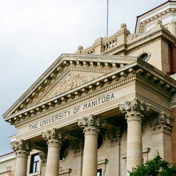 The University of Manitoba building has a beige facade with columns.