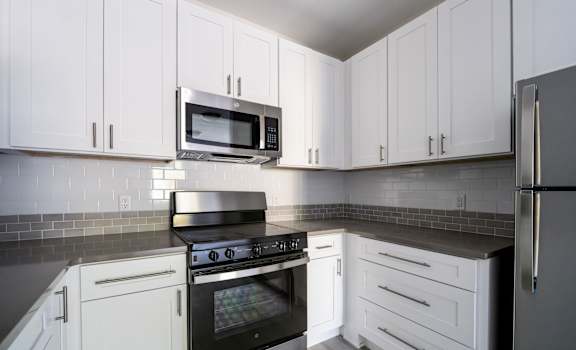 A kitchen with white cabinets and a black stove top oven.