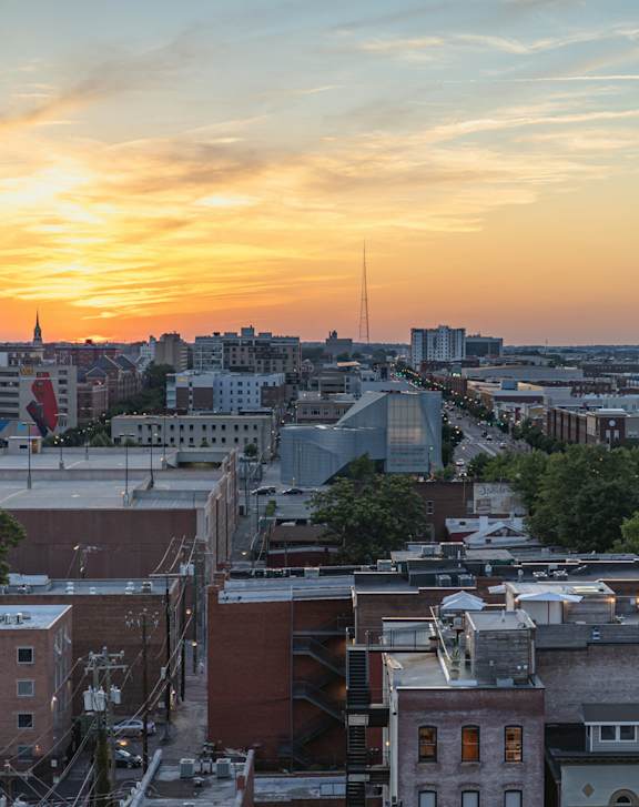 A cityscape at sunset with buildings of various sizes and shapes.
