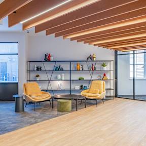 A room with a yellow chair and a wooden floor.