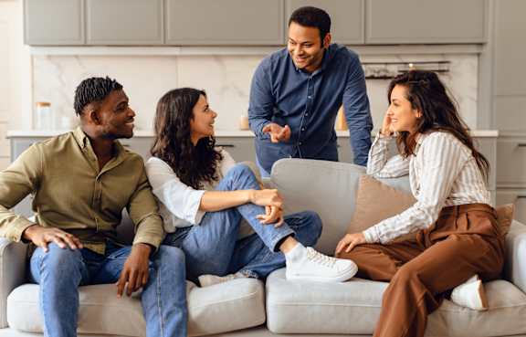 Four people sitting on a couch in a living room.