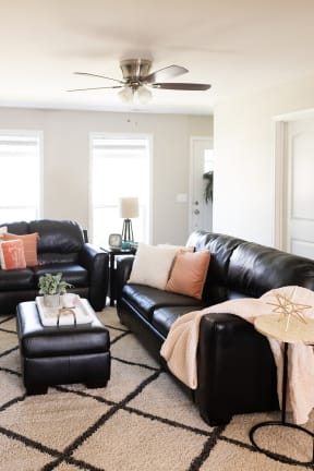 a living room with black leather couches and a beige rug