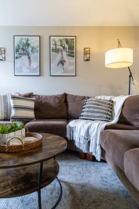 a living room with a brown couch and pictures on the wall