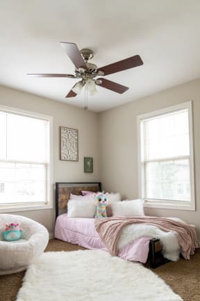 a bedroom with two windows and a ceiling fan