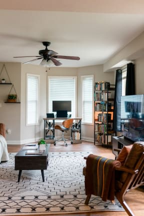 a living room with a ceiling fan and a desk with a computer on it