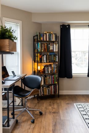 a home office with a bookcase filled with books and a laptop on a desk