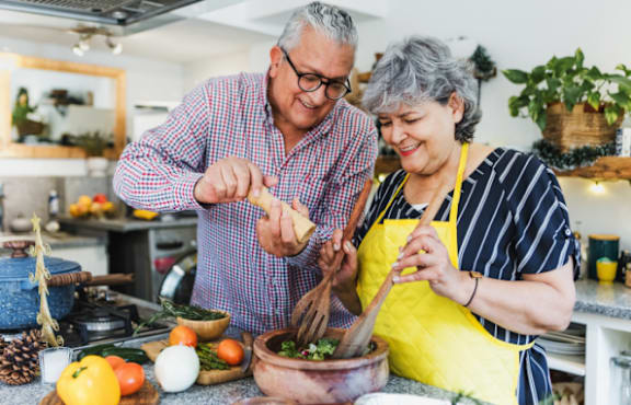 Man and Woman Smiling while Cooking Together in Kitchen
