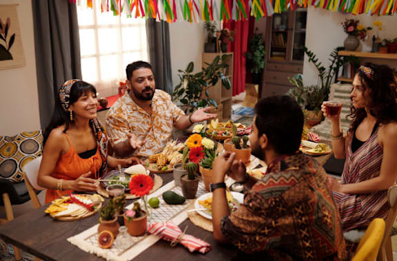Friends Smiling while Sitting Around Dinner Table Together