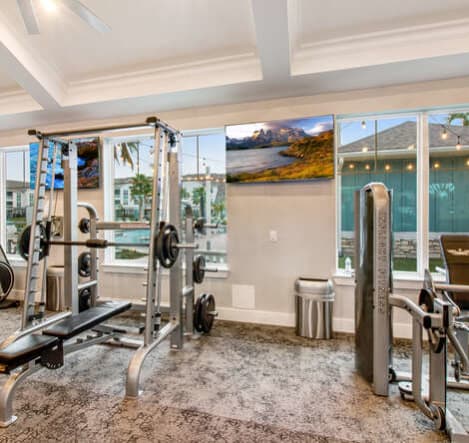 A gym with treadmills and other exercise equipment in a large room with windows at Watermark at Urban Blu, Panama City Beach, Florida