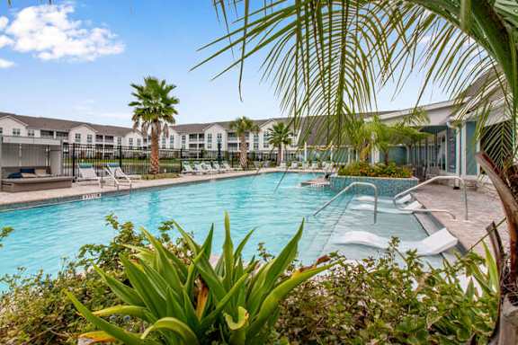 a large swimming pool with chairs and palm trees at Watermark at Urban Blu, Panama City Beach, Florida