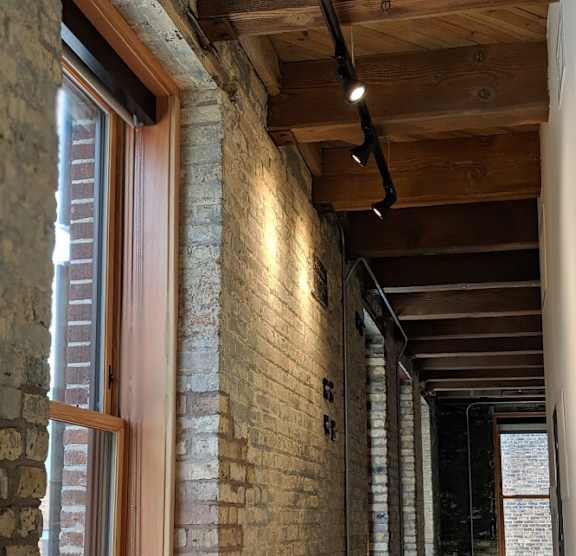 A long hallway with brick walls and wooden beams on the ceiling.
