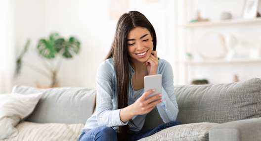 a woman sitting on a couch looking at her cell phone