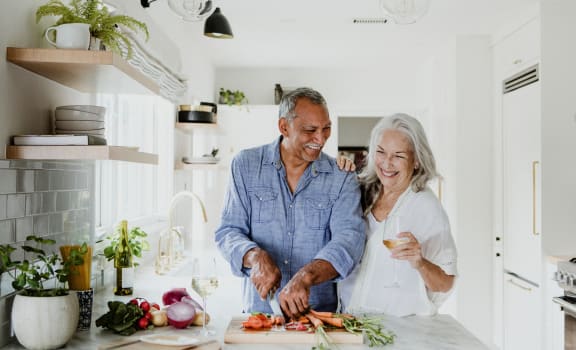 a man and a woman in a kitchen cutting vegetables