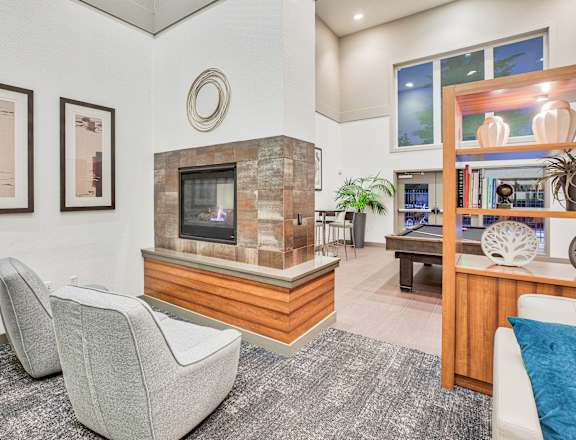 A living room with a grey carpet and a stone fireplace.