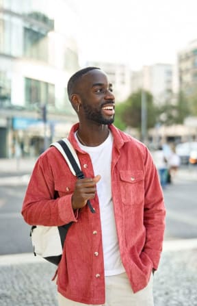 a man walking down the street wearing a red jacket and a backpack