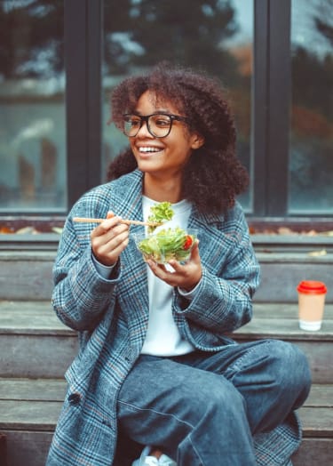 a woman sitting on the steps eating a salad