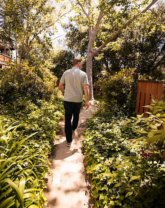 A man and a woman are walking on a path in the woods.