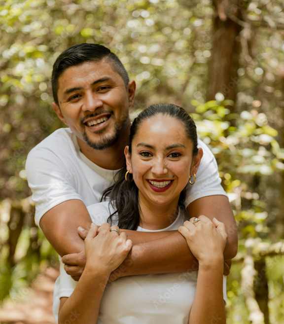 A man and woman hugging each other in a forest.