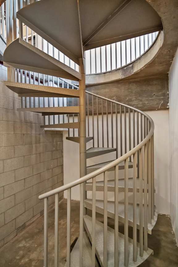 A spiral staircase with a white railing and a beige wall at Fusion Hollywood.