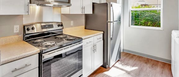 A kitchen with a stove, refrigerator, and cabinets.
